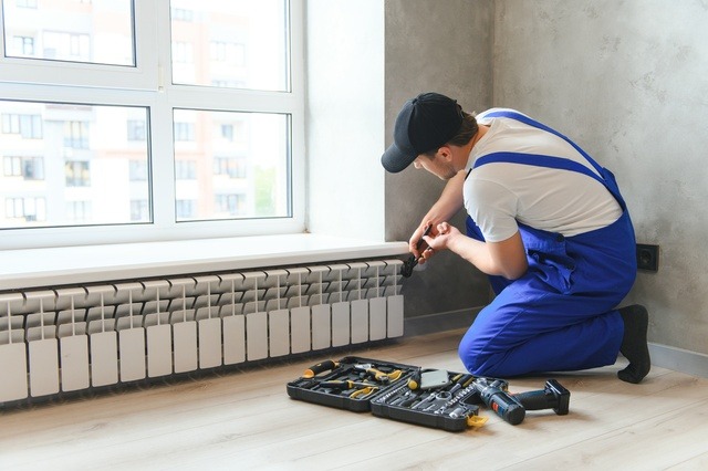 Cheerful Male Worker, Plumber Checking Pipes While Installing Heating System In Apartment